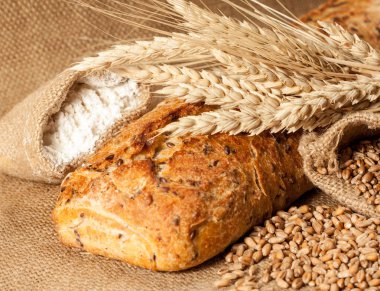 Retro bread in rustic style background.Fresh traditional bread on wooden ground with flour in a sack.