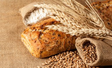 Retro bread in rustic style background.Fresh traditional bread on wooden ground with flour in a sack.