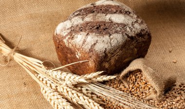 Retro bread in rustic style background.Fresh traditional bread on wooden ground with flour in a sack.