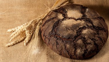Retro bread in rustic style background.Fresh traditional bread on wooden ground with flour in a sack.