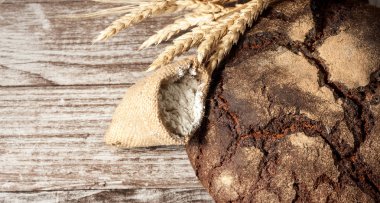 Retro bread in rustic style background.Fresh traditional bread on wooden ground with flour in a sack.