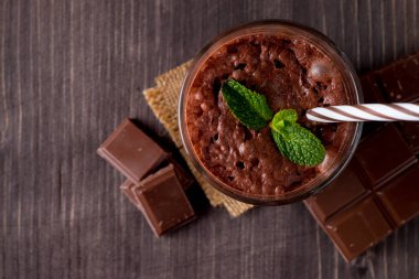 Çikolata, kahve, süt, muz sallamak ahşap arka plan üzerinde. Nane ile güler yüzlü. Milkshake. Protein diyeti. Sağlıklı yiyecek ve içecek konsepti.