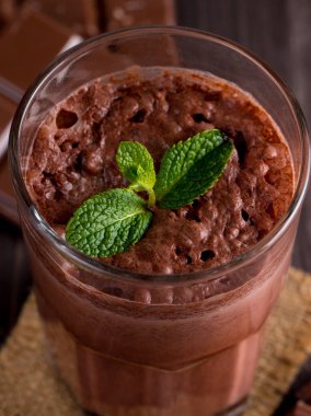 Çikolata, kahve, süt, muz sallamak ahşap arka plan üzerinde. Nane ile güler yüzlü. Milkshake. Protein diyeti. Sağlıklı yiyecek ve içecek konsepti.