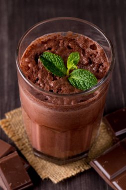 Çikolata, kahve, süt, muz sallamak ahşap arka plan üzerinde. Nane ile güler yüzlü. Milkshake. Protein diyeti. Sağlıklı yiyecek ve içecek konsepti.