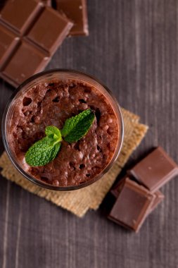 Çikolata, kahve, süt, muz sallamak ahşap arka plan üzerinde. Nane ile güler yüzlü. Milkshake. Protein diyeti. Sağlıklı yiyecek ve içecek konsepti.