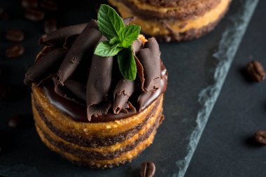 Çikolatalı kek siyah slatter kurulu ile nane, kahve çekirdekleri koyu arka plan, closeup fotoğraf üzerinde. Taze, lezzetli tatlı gıda kavramı. 