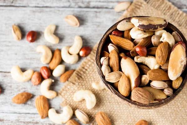Healthy mix nuts on wooden background. Almonds, hazelnuts, cashews, peanuts, pistachios, brazilian nuts