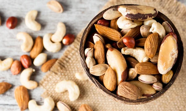 Healthy mix nuts on wooden background. Almonds, hazelnuts, cashews, peanuts, pistachios, brazilian nuts