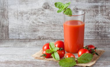 Bir bardak domates suyu ahşap Sivas'tan zemin üzerine sebzeli close-up. Vitamin ve mineraller. Sağlıklı içecek konsepti.