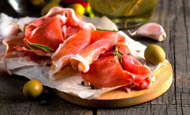 prosciutto ile karışık zeytin ve ahşap kesme tahtası üzerinde kırmızı biber ince dilim closeup