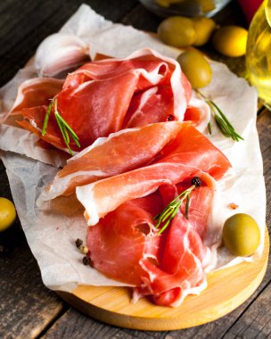prosciutto ile karışık zeytin ve ahşap kesme tahtası üzerinde kırmızı biber ince dilim closeup