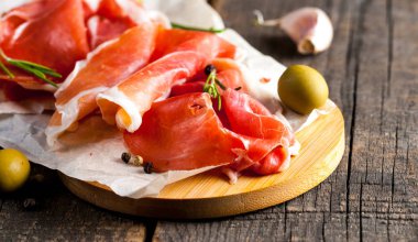 prosciutto ile karışık zeytin ve ahşap kesme tahtası üzerinde kırmızı biber ince dilim closeup