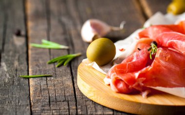 prosciutto ile karışık zeytin ve ahşap kesme tahtası üzerinde kırmızı biber ince dilim closeup