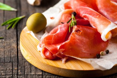 prosciutto ile karışık zeytin ve ahşap kesme tahtası üzerinde kırmızı biber ince dilim closeup