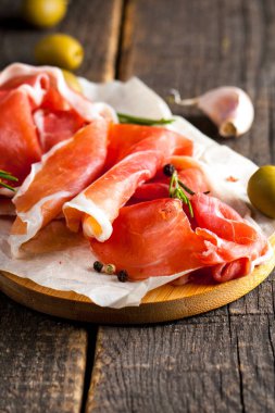 prosciutto ile karışık zeytin ve ahşap kesme tahtası üzerinde kırmızı biber ince dilim closeup