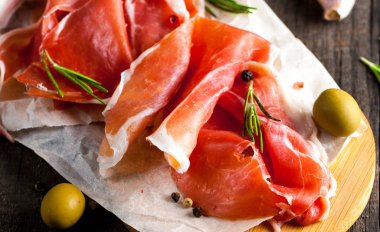 prosciutto ile karışık zeytin ve ahşap kesme tahtası üzerinde kırmızı biber ince dilim closeup