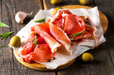 prosciutto ile karışık zeytin ve ahşap kesme tahtası üzerinde kırmızı biber ince dilim closeup