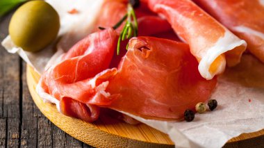 prosciutto ile karışık zeytin ve ahşap kesme tahtası üzerinde kırmızı biber ince dilim closeup