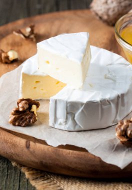 Brie peyniri. Camembert peyniri. Taze Brie peyniri ve tahtadan bir dilim fındık, bal ve yaprakla. İtalyan, Fransız peyniri.