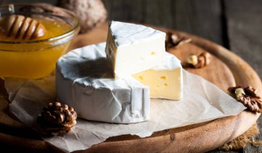 Brie peyniri. Camembert peyniri. Taze Brie peyniri ve tahtadan bir dilim fındık, bal ve yaprakla. İtalyan, Fransız peyniri.