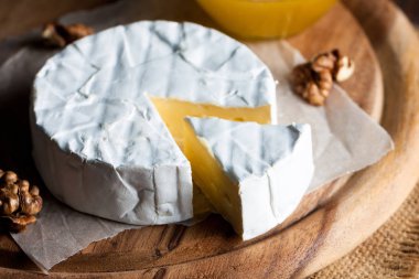 Brie peyniri. Camembert peyniri. Taze Brie peyniri ve tahtadan bir dilim fındık, bal ve yaprakla. İtalyan, Fransız peyniri.