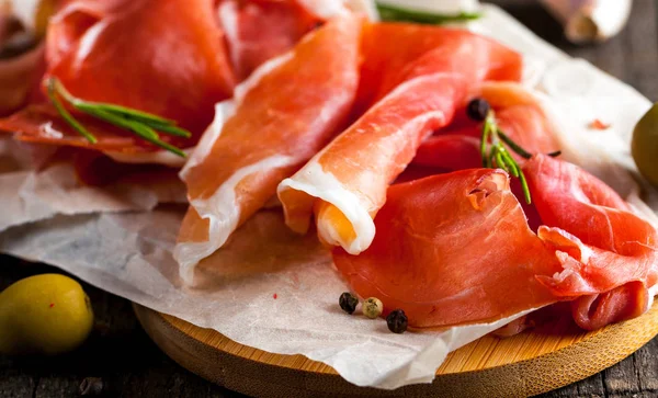 prosciutto ile karışık zeytin ve ahşap kesme tahtası üzerinde kırmızı biber ince dilim closeup