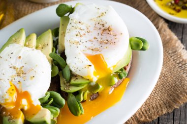 Avokado tost, kiraz domates ahşap arka plan üzerinde. Kahvaltı tost avokado, Vejetaryen gıda, sağlıklı beslenme kavramı ile. Avokado ve haşlanmış yumurta ile sağlıklı sandviç.