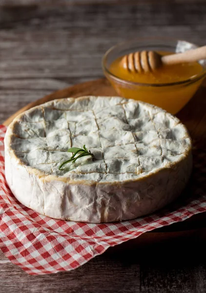 Brie type of cheese. Camembert cheese. Fresh Brie cheese and a slice on a wooden board with nuts, honey and leaves. Italian, French cheese.