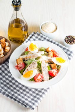 Taze salata domates, ruccola, tavuk göğsü, yumurta, roka, kraker ve baharat yapılmış. Ahşap arka plan üzerinde beyaz, şeffaf bir kasede Sezar salatası