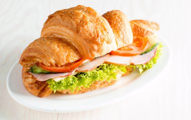 Taze kruvasan veya sandviç salata, jambon, jamon, jambon, salam, peynir, tavuk, domates ahşap arka plan ile. Sabah kahvaltı kavramı. Sağlıklı ve fast food.