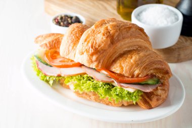 Taze kruvasan veya sandviç salata, jambon, jamon, jambon, salam, peynir, tavuk, domates ahşap arka plan ile. Sabah kahvaltı kavramı. Sağlıklı ve fast food.