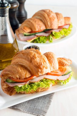 Taze kruvasan veya sandviç salata, jambon, jamon, jambon, salam, peynir, tavuk, domates ahşap arka plan ile. Sabah kahvaltı kavramı. Sağlıklı ve fast food.