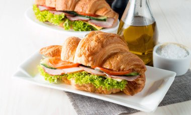 Taze kruvasan veya sandviç salata, jambon, jamon, jambon, salam, peynir, tavuk, domates ahşap arka plan ile. Sabah kahvaltı kavramı. Sağlıklı ve fast food.