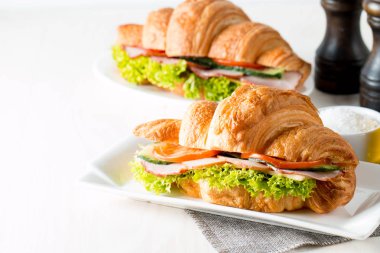 Taze kruvasan veya sandviç salata, jambon, jamon, jambon, salam, peynir, tavuk, domates ahşap arka plan ile. Sabah kahvaltı kavramı. Sağlıklı ve fast food.