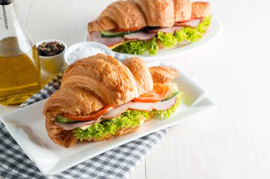 Taze kruvasan veya sandviç salata, jambon, jamon, jambon, salam, peynir, tavuk, domates ahşap arka plan ile. Sabah kahvaltı kavramı. Sağlıklı ve fast food.