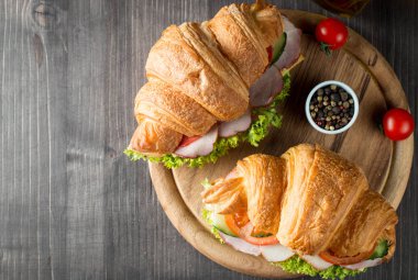 Taze kruvasan veya sandviç salata, jambon, jamon, jambon, salam, peynir, tavuk, domates ahşap arka plan ile. Sabah kahvaltı kavramı. Sağlıklı ve fast food.