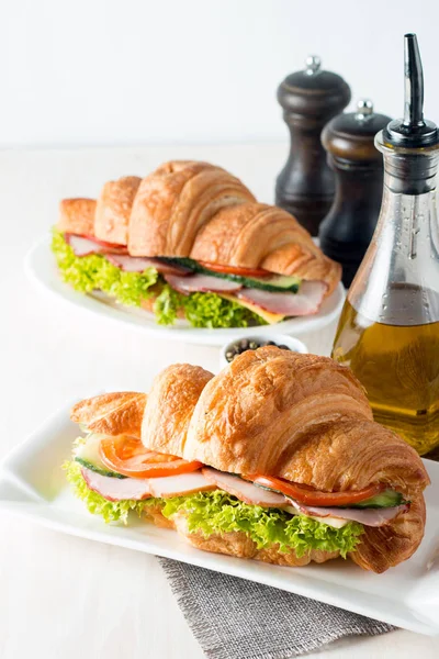 Taze kruvasan veya sandviç salata, jambon, jamon, jambon, salam, peynir, tavuk, domates ahşap arka plan ile. Sabah kahvaltı kavramı. Sağlıklı ve fast food.