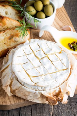 Pişmiş camembert peyniri. Taze Brie peyniri ve bir dilim fındık, tatlım, biberiye ile ahşap bir gemide, baget ekmek ızgara tost ve yaprakları. Peynir Brie türü. İtalyan, Fransız peynir.