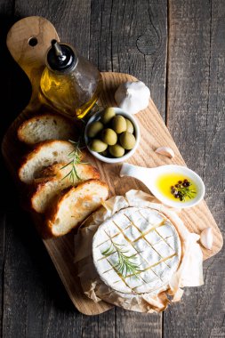 Pişmiş camembert peyniri. Taze Brie peyniri ve bir dilim fındık, tatlım, biberiye ile ahşap bir gemide, baget ekmek ızgara tost ve yaprakları. Peynir Brie türü. İtalyan, Fransız peynir.