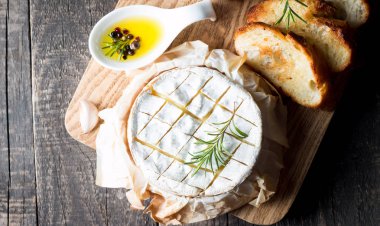 Pişmiş camembert peyniri. Taze Brie peyniri ve bir dilim fındık, tatlım, biberiye ile ahşap bir gemide, baget ekmek ızgara tost ve yaprakları. Peynir Brie türü. İtalyan, Fransız peynir.