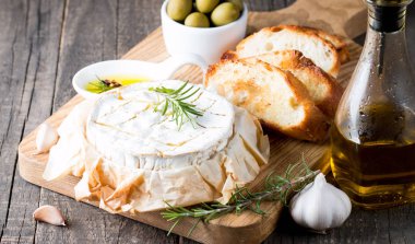 Pişmiş camembert peyniri. Taze Brie peyniri ve bir dilim fındık, tatlım, biberiye ile ahşap bir gemide, baget ekmek ızgara tost ve yaprakları. Peynir Brie türü. İtalyan, Fransız peynir.