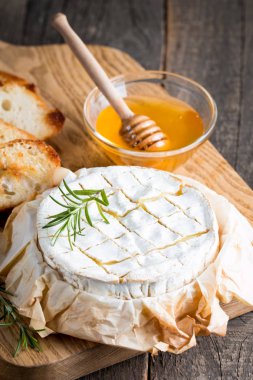 Pişmiş camembert peyniri. Taze Brie peyniri ve bir dilim fındık, tatlım, biberiye ile ahşap bir gemide, baget ekmek ızgara tost ve yaprakları. Peynir Brie türü. İtalyan, Fransız peynir.