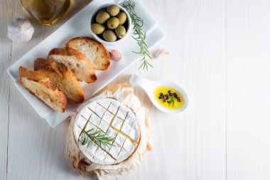 Pişmiş camembert peyniri. Taze Brie peyniri ve bir dilim fındık, tatlım, biberiye ile ahşap bir gemide, baget ekmek ızgara tost ve yaprakları. Peynir Brie türü. İtalyan, Fransız peynir.