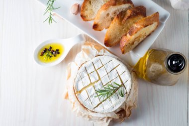 Pişmiş camembert peyniri. Taze Brie peyniri ve bir dilim fındık, tatlım, biberiye ile ahşap bir gemide, baget ekmek ızgara tost ve yaprakları. Peynir Brie türü. İtalyan, Fransız peynir.