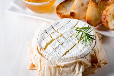 Pişmiş camembert peyniri. Taze Brie peyniri ve bir dilim fındık, tatlım, biberiye ile ahşap bir gemide, baget ekmek ızgara tost ve yaprakları. Peynir Brie türü. İtalyan, Fransız peynir.