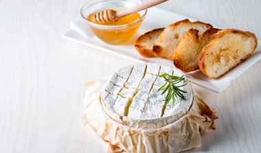 Pişmiş camembert peyniri. Taze Brie peyniri ve bir dilim fındık, tatlım, biberiye ile ahşap bir gemide, baget ekmek ızgara tost ve yaprakları. Peynir Brie türü. İtalyan, Fransız peynir.