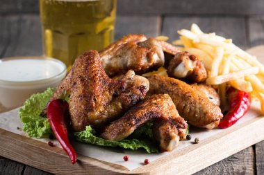 Yakın çekim fotoğraf Barbekü tavuk kanatlı patates ve bira. Barbekü soslar, ketçap, mayonez etli. Hızlı ve abur cubur kavramı. 