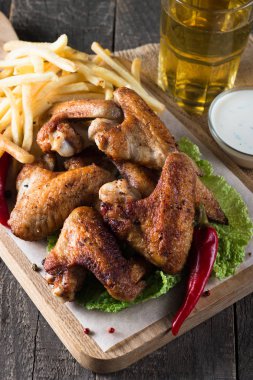 Yakın çekim fotoğraf Barbekü tavuk kanatlı patates ve bira. Barbekü soslar, ketçap, mayonez etli. Hızlı ve abur cubur kavramı. 