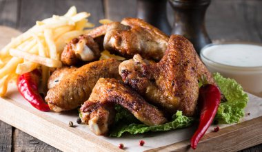 Yakın çekim fotoğraf Barbekü tavuk kanatlı patates ve bira. Barbekü soslar, ketçap, mayonez etli. Hızlı ve abur cubur kavramı. 