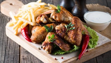 Yakın çekim fotoğraf Barbekü tavuk kanatlı patates ve bira. Barbekü soslar, ketçap, mayonez etli. Hızlı ve abur cubur kavramı. 